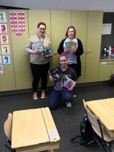 Kuvassa kolme kirjaston työntekijää vinkkaamassa lastenkirjoja.